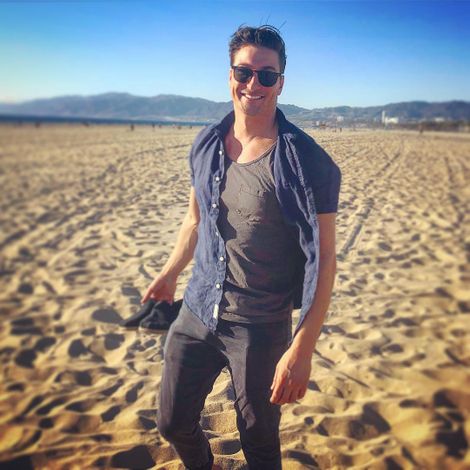 Daniel Lissing posing barefoot on sand larger surfaces