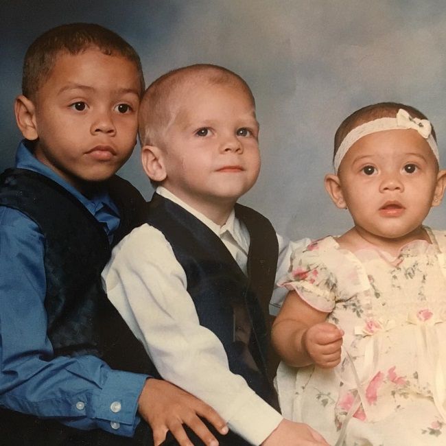 Picture of Chris Daniels with his brother Davion and sister Ariana posing for a photoshoot wearing black blazer and white shirt