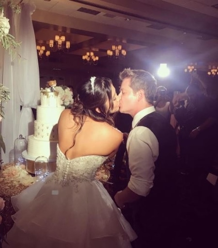 Jason Earles and Katie Drysen kissing each other before cutting the cake at their after wedding party