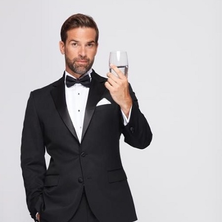 Gethin Jones while on photo shoot holding a glass of water on a black and white suit