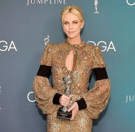 harlize Theron who owns a net worth of around $160 million poses with Costume Designer’s Guild Awards (CDGA).