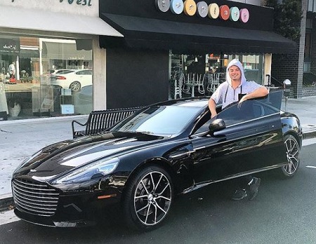 The entrepreneur, philanthropist, Sean Lourdes poses with his Aston Martin Car.