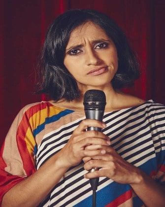 Preetha Jobrani wearing mixed coloured vest and holding a black mike.