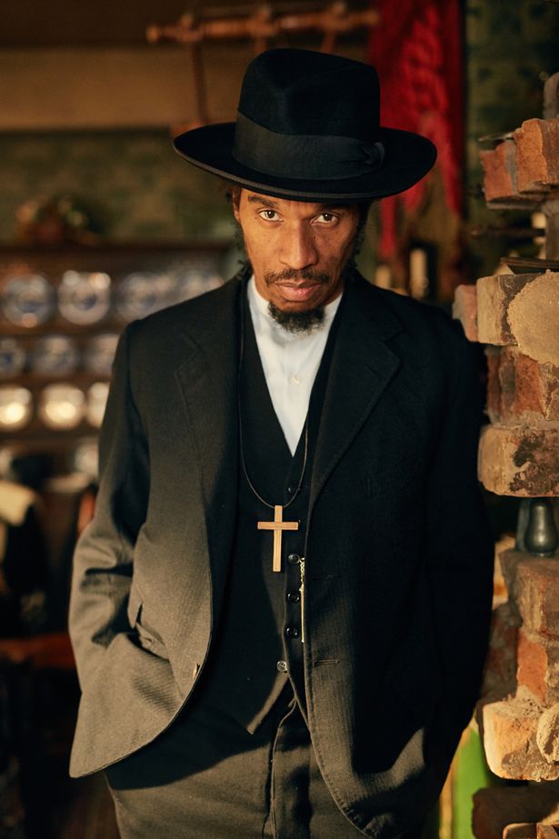 Benjamin Zephaniah wearing black coat, pant and  white shirt and hat
