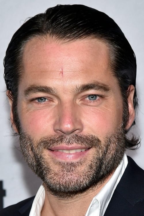 Photo of Tim Rozon wearing a black coat and a white shirt.