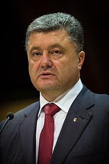Photo of Petro Poroshenko wearing a black coat, white shirt and a red tie.
