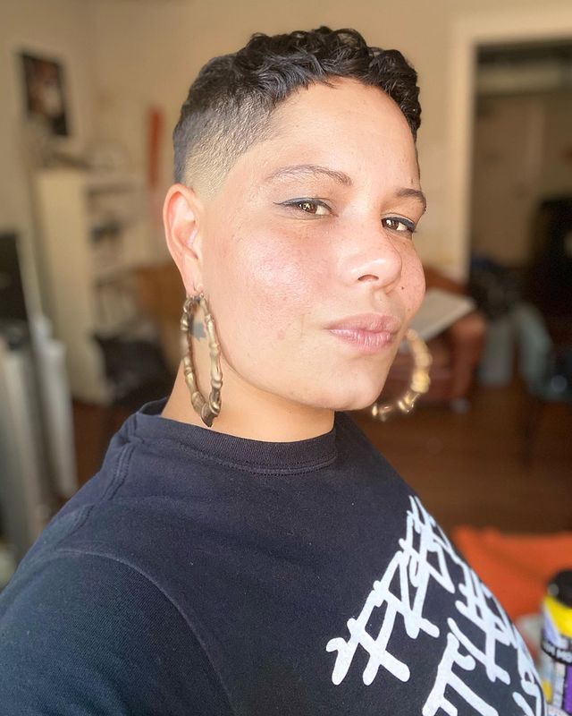 Nikkita Oliver posing for her Instagram feed by wearing black vest and golden earrings.