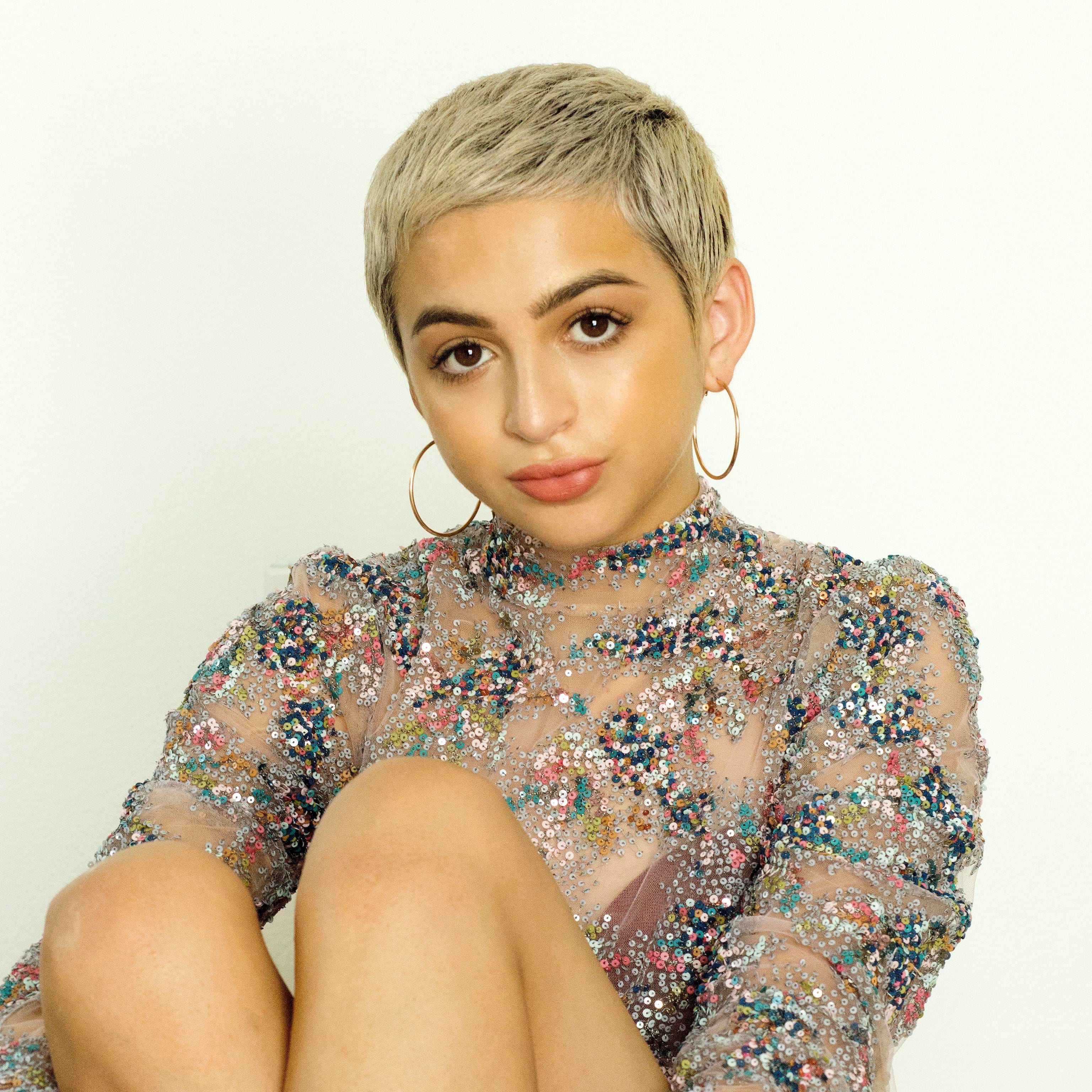 Josie Totah posing for a photoshoot by sitting on the ground.