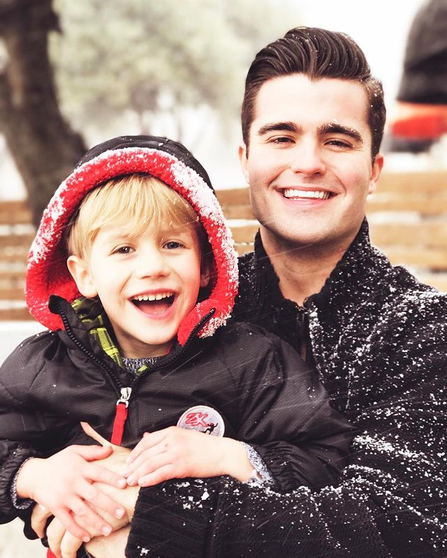 Spencer wearing black jacket cover by snow and his kid wearing black and red jacket.