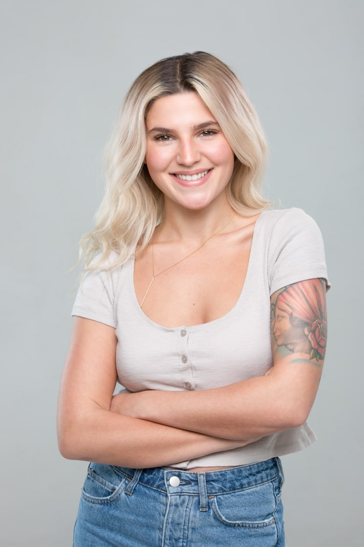 Carly Aquilino posing wearing pink t shirt and jeans with folding hands