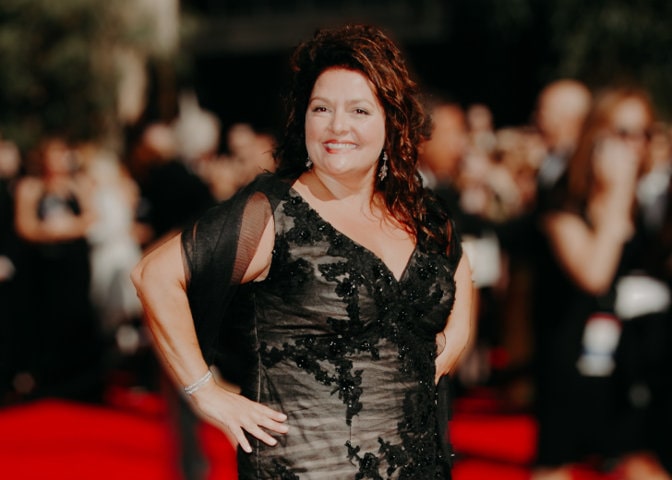 Aida Turturro wearing black dress and in a curly hair.