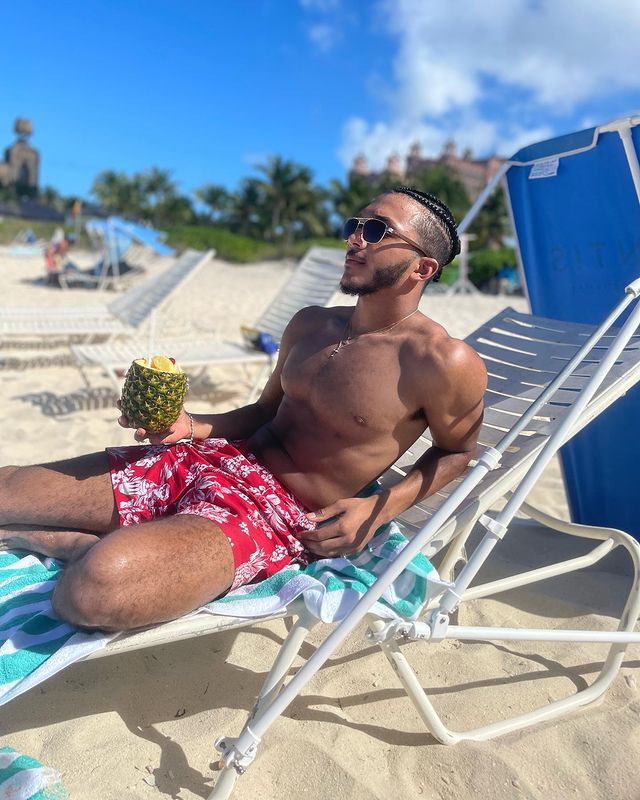 Gabriel Hostin posing in a beach drinking pineapple Juice