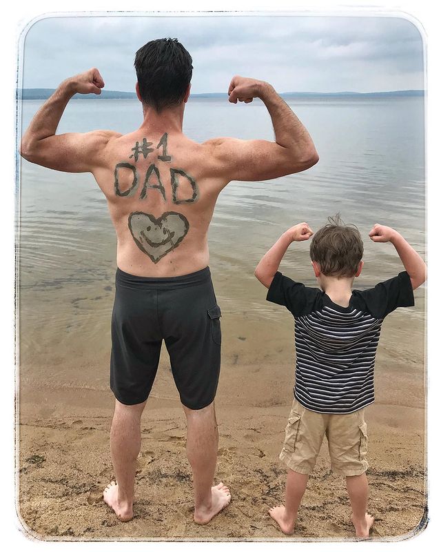 Dan Jeannotte  posing for a photo with his son turning back  on the beach in the same pose by turning back and have written # No.1dad on his back.