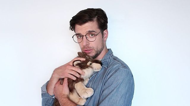 Dan Jeannotte  posing for a photo with a little dog holding on his chest with wearing glasses