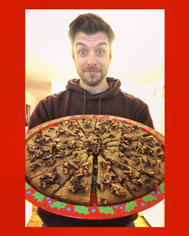 Dan Jeannotte  posing for a photo with carrying  pizza sized and shaped cookies in his hand
