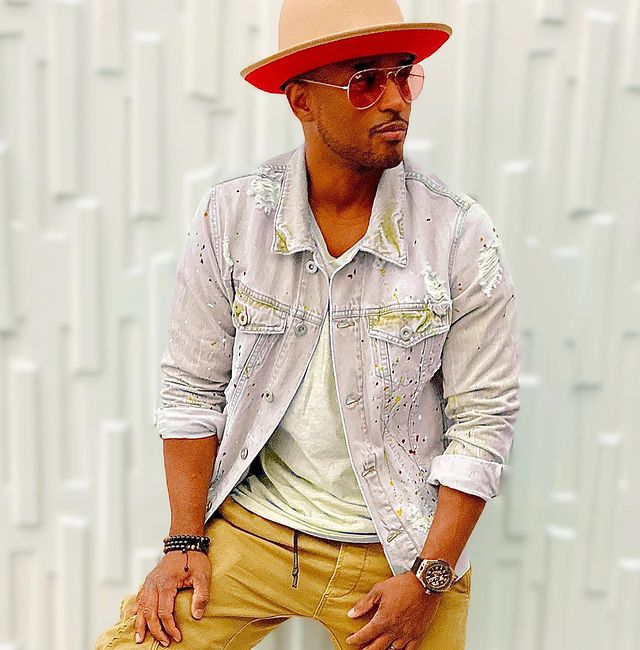Pictures of Larenz Tate posing for a photoshoot wearing brown pants with jacket and red hat