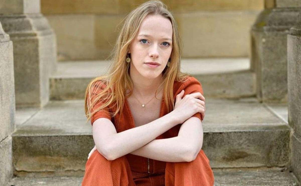 Amybeth McNulty posing for photo sitting with a folded hand wearing orange jumpsuit