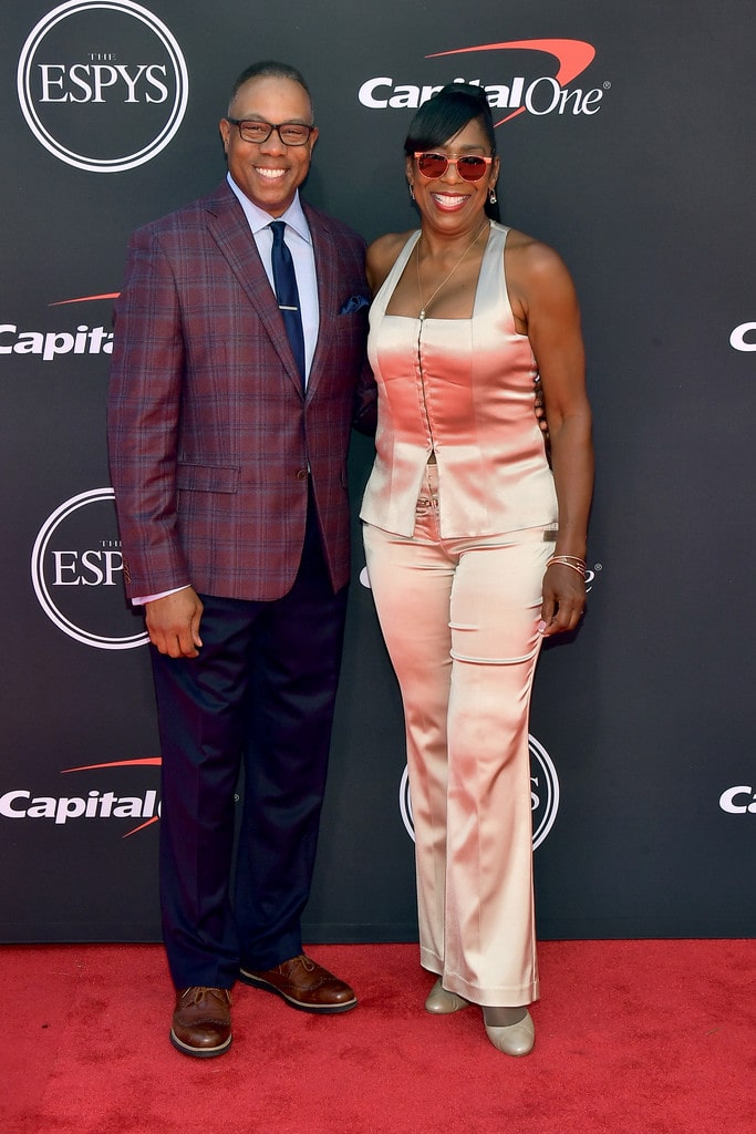 Dawnn Lewis with her husband Johnny Newman wearing light pink jump suite with a long earring and short black hair with a smiley face