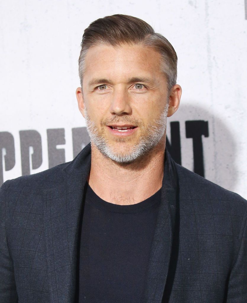 Jeff Hephner posing for the photo in a short white beard and hair wearing black coat and black tshirt