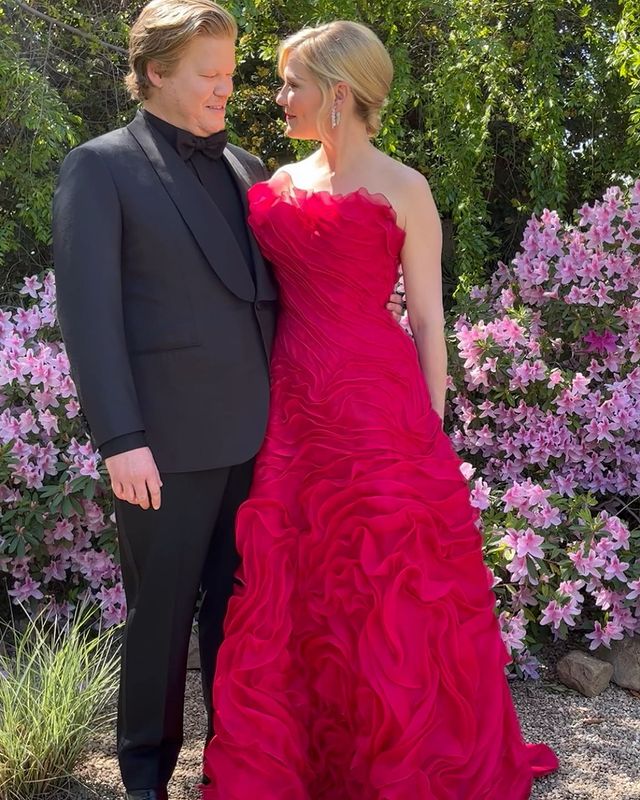 Picture of James  Robert Plemons parents posing for a photoshoot wearing red gown and black color blazer