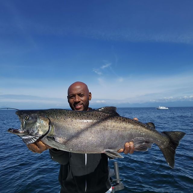 Romany Malco posing for a photoshoot with Chinook salmon.