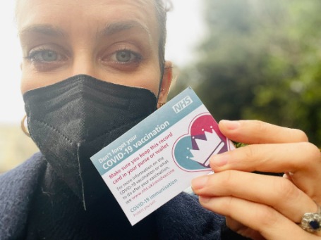 Photo of Luke Treadaway while holding her vaccination card. 