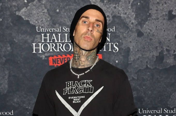 Photo of Travis Landon Barker wearing cap and necklace with black T-shirt