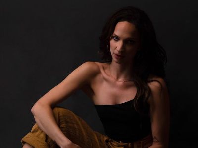 Ruby Modine is wearing a black right sleeveless top and brown pants in the picture.