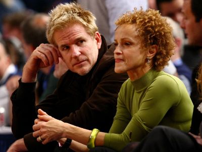 Both Caridad Rivera and Matthew Modine are sitting and watching something.